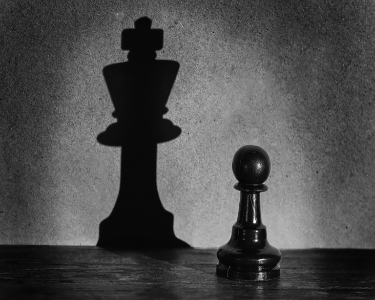 Chess pawn standing in a spotlight that make a shadow actistic | NSI